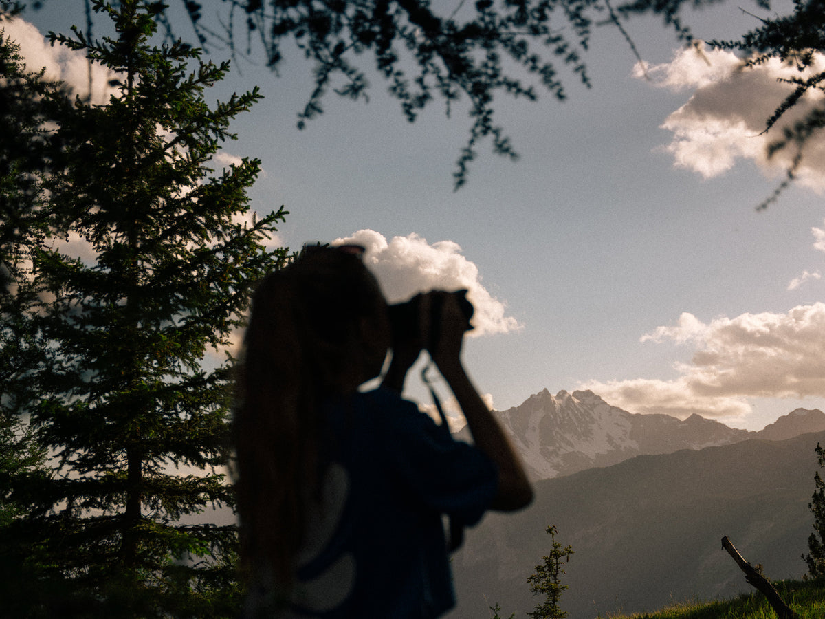 Rose avec son appareil photo devant les montagnes.