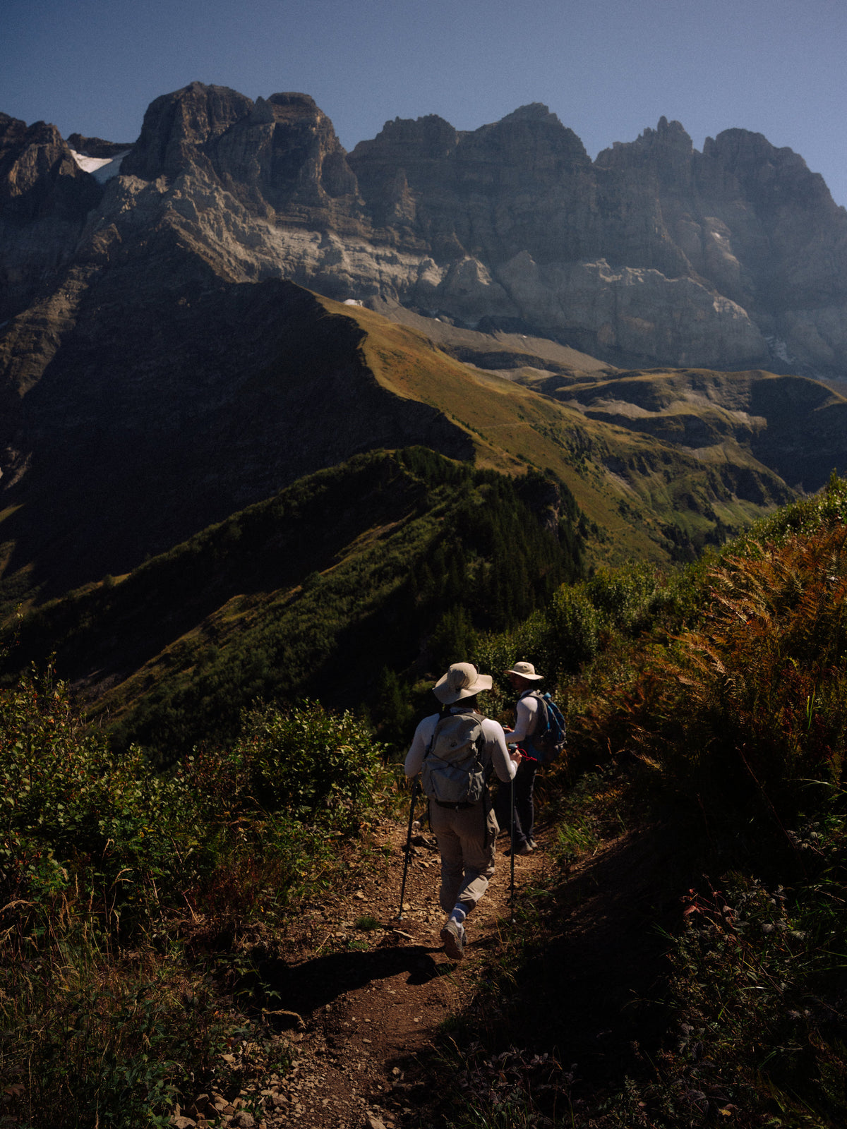 Deux silhouettes sur un sentier sous les montagnes.